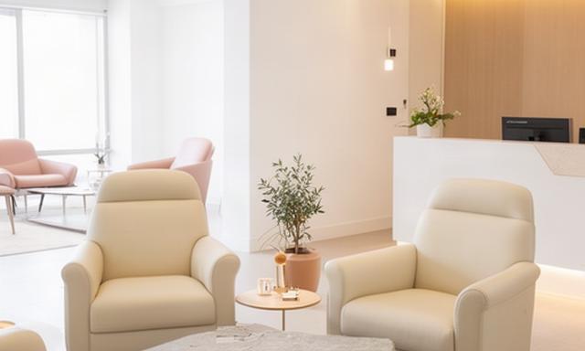 Area attesa di una clinica estetica con poltrone in pelle color crema e tavolino in pietra