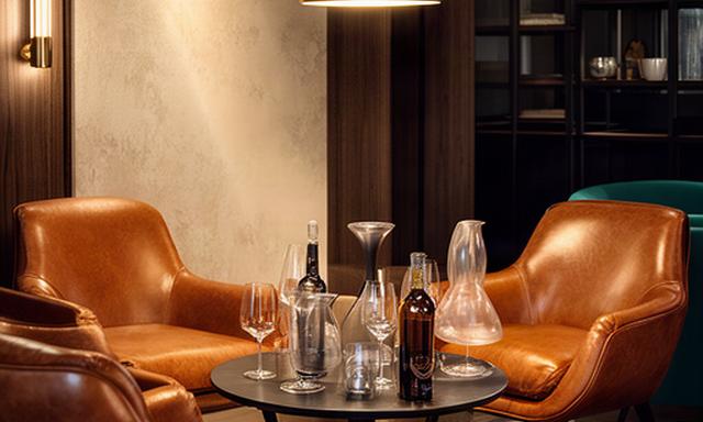 Area lounge di un wine bar con poltrone in pelle color cognac e tavolino per degustazione