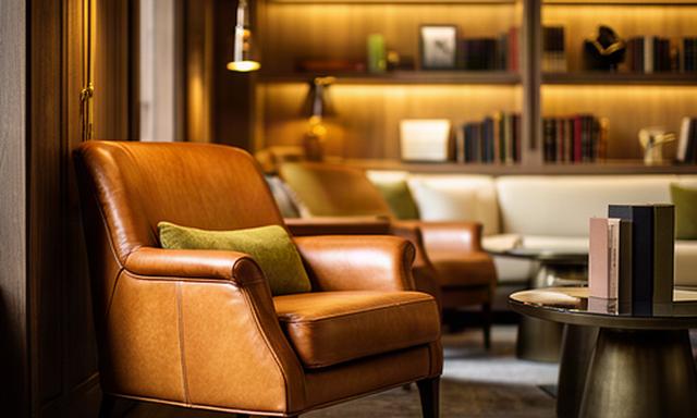 Lounge di un hotel boutique in Lombardia con poltrone in pelle cognac e libreria illuminata